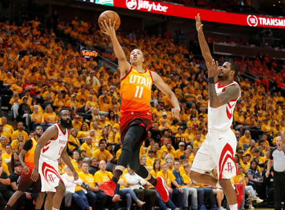 El base Dante Exum (11), del Jazz de Utah, salta hacia la canasta mientras el alero Trevor Ariza, de los Rockets de Houston intenta bloquearlo durante un partido de postemporada en Salt Lake City. (AP) 