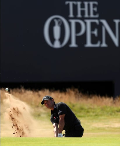 El estadounidense Kevin Kisner sale de una trampa de arena en el 18vo hoyo en la primera ronda del Abierto británico de Golf en Carnoustie. Johnson y Kisner comparten casa y cima. (ARCHIVO)