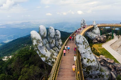 Varios turistas cruzan el nuevo puente Cau Vang (Puente Dorado), construido sobre la estructura gigante de unas manos, sobre las colinas Ba Na. (ARCHIVO)