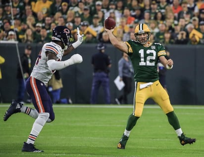 Aaron Rodgers (d) tuvo que salir por una lesión en la rodilla, pero volvió en la segunda mitad y lanzó tres pases de anotación en el último cuarto. (AP)