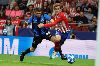 El delantero francés del Atlético de Madrid, Antoine Griezmann (d), se lleva el balón ante el defensa del Brujas KV, Brandon Mechele.