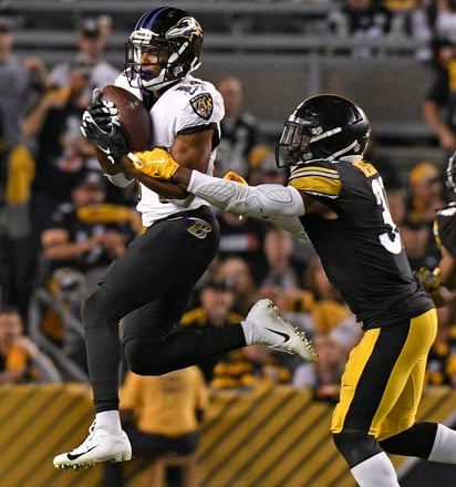 El receptor de los Ravens de Baltimore, Tim White (i) atrapa un pase frente al defensivo de los Steelers de Pittsburgh, Terrell Edmunds.