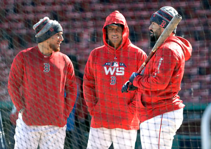 El manager de los Medias Rojas de Boston Alex Cora, en el medio, charla con los receptores Christian Vázquez (izquierda) y Sandy León (derecha) durante un entrenamiento en Fenway Park.