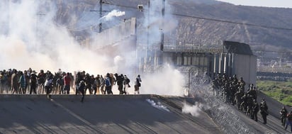 Alrededor de 500 migrantes centroamericanos se lanzaron ayer domingo sobre la valla fronteriza que divide a México de Estados Unidos, en Tijuana, pero desistieron de cruzar al ser alcanzados por gases lacrimógenos y balas de goma que lanzaron desde el norte. (EFE)