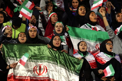 Aficionadas iraníes ondean banderas desde las tribunas durante el partido amistoso entre Irán y Bolivia.