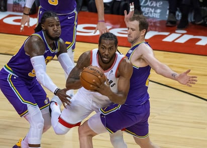 Kawhi Leonard (c) de Toronto Raptors trata de pasar el balón ante la marca de Jae Crowder (i) y Joe Ingles de Utah Jazz.