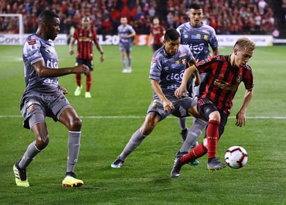 Ezequiel Barco juega el balón frente a defensores del Herediano.