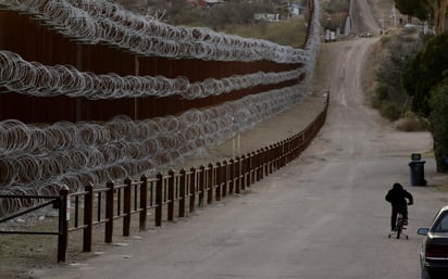 Un niño anda en bicicleta junto al muro cubierto de alambre de púas que separa a Nogales, Arizona, de Nogales, Sonora.