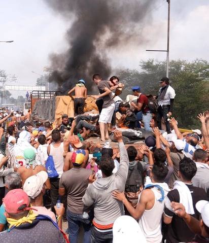 El NYT señala cómo en el aire se desprende parte de ese cóctel Molotov, en llamas, y un trozo cae cerca del camión que se incendió. (EFE)