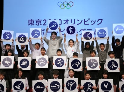 Shota Iizuka (centro a la izquierda), medallista de plata de atletismo en los Juegos de Río 2014, y la karateca Kiyo Shimizu, (centro a la derecha) posan junto a estudiantes con los pictogramas de los Juegos Olímpicos de Tokio 2020 durante un acto para celebrar la cuenta regresiva de 500 días para las justas.