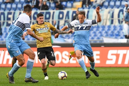 El brasileño Lucas Leiva (d) pelea el balón con el mediocampista argentino del Udinese Rodrigo de Paul (c).