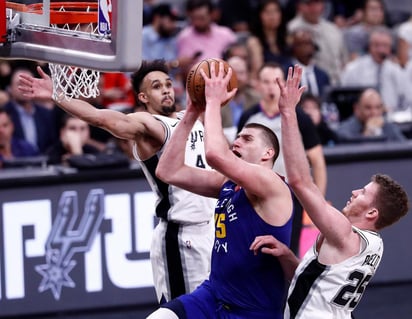 El jugador serbio de los Nuggets de Denver, Nikola Jokic (c), va a la canasta contra los jugadores de los San Antonio Spurs Derrick White (i) y Jakob Poeltl.