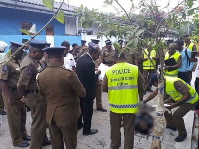 Los oficiales de seguridad inspeccionan un cuerpo en el sitio después de un tiroteo en Sainthamarudu.