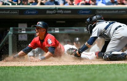 El venezolano Ehire Adrianza, de los Mellizos de Minnesota, se desliza para anotar frente a Omar Narváez, de los Marineros de Seattle. (AP)