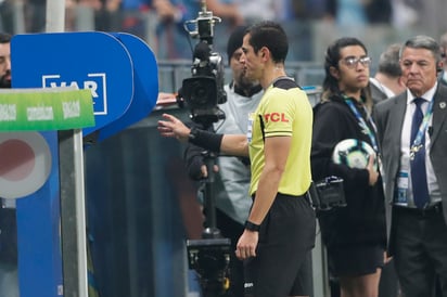 El árbitro Andrés Rojas observa el monitor del VAR durante un partido de la Copa América entre Uruguay y Japón. (AP)