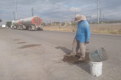 A cambio de una propina, el hombre tapaba los baches que hay en la carretera Madero-Florida para evitar daños en los vehículos. (MARY VÁZQUEZ)