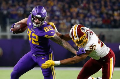 El ala cerrada Kyle Rudolph (82) se quita la marca del liniero Montez Sweat (90) durante el partido entre Minnesota y Washington. (AP)