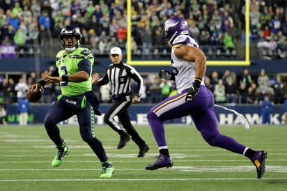 Russell Wilson (i) lanzó para 240 yardas y tuvo dos pases de anotación frente a los Vikingos. (AP)