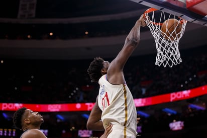 Joel Embiid (21) realiza una clavada ante la mirada espectante del estelar jugador griego Giannis Antetokounmpo en el duelo de ayer. (AP)