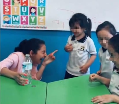 Una de sus alumnas acepta el reto y al poner uno de sus ojos para observar la moneda por la boca de la botella destapada, la maestra aprieta con ambas manos el recipiente de plástico, y el chorro de agua salta con fuerza mojándole el rostro y la ropa. (ESPECIAL)
