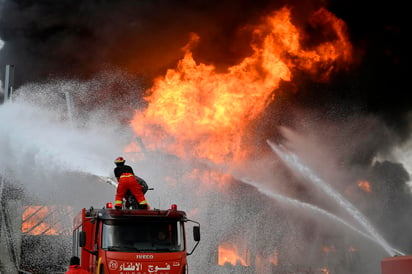 Una columna de humo negro se elevaba desde el puerto, con llamas anaranjadas que saltaban desde el piso. (EFE)