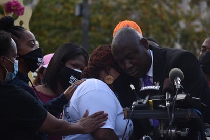 El abogado de la familia de Breonna Taylor, Ben Crump (d), abraza a la madre, Tamika Palmer (c), durante una rueda de prensa hoy en Louisville, Kentucky.