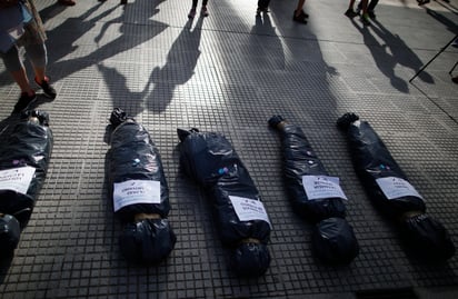 Los manifestantes simularon, usando bolsas, cuerpos de personas fallecidas con los nombres de aquellos que recibieron las vacunas . (AP) 