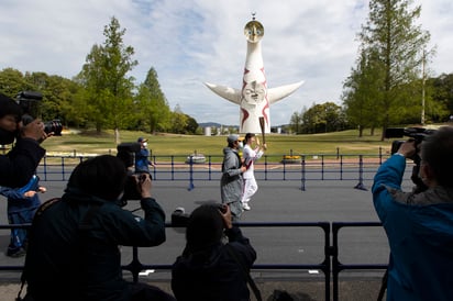 La exatleta olímpica Aya Terakawa (c) corre con la antorcha olímpica durante el primer día de la ronda de relevos en un antiguo sitio de ferias en Suita, al norte de Osaka, Japón. (AP)