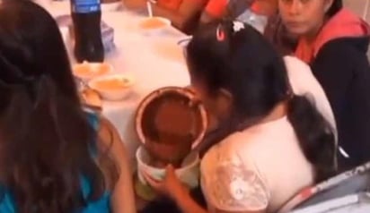 En un 'tupper' la mujer vació la comida que le habían servido, lo que llamó la atención de la persona que grababa (CAPTURA) 