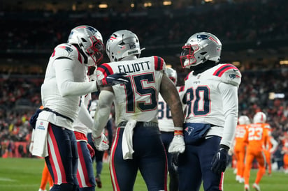 Ezekiel Elliott (15), running back de los Patriots de Nueva Inglaterra, es felicitado por sus compañeros de equipo después de anotar un touchdown durante la segunda mitad del juego de la NFL en contra de los Broncos de Denver, el domingo 24 de diciembre de 2023, en Denver. (AP Foto/David Zalubowski)


