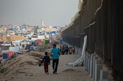 Palestinos desplazados caminan cerca del muro con Egipto en Rafah, ciudad de Gaza. (ARCHIVO)