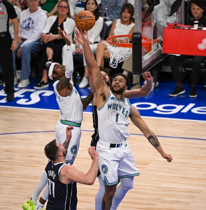 Kyle Anderson de los Minnesota Timberwolves (C), disputa la pelota con el acoso de jugadores de los Dallas Mavericks en el Target Center.