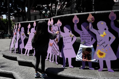 Una niña observa una silueta de madera con nombres de personas desaparecidas en el estado de Puebla (México).  EFE/ Hilda Ríos.