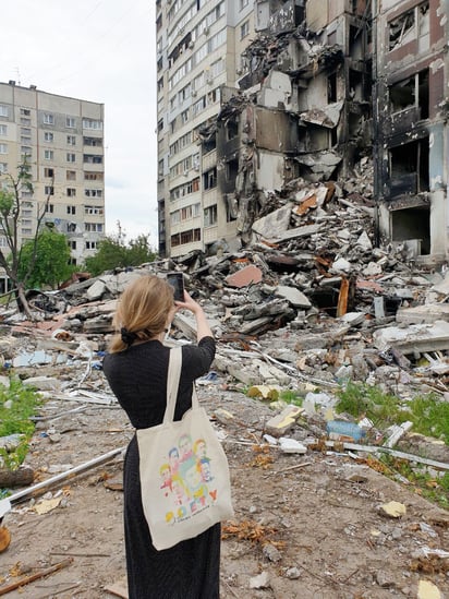 Victoria Amelina fotografiando una zona
bombardeada de Ucrania. Lleva un bolso con
el rostro de destacados poetas ucranianos. Crédito: Twitter/ Victoria Amelina