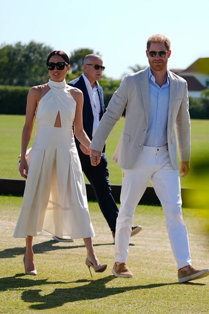 Meghan Markle luciendo un atuendo de Heidi Merrick de la mano del príncipe Harry.