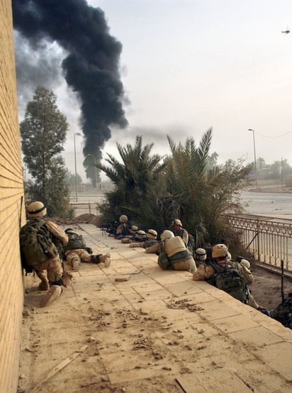 Soldados estadounidenses ven arder un edificio en Bagdad durante la invasión a Irak en 2003. Foto: Andrew Kosterman