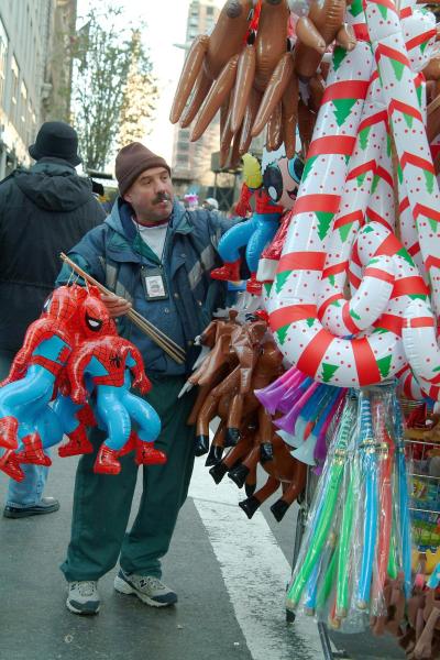 Un vendedor de juguetes y globos con figuras de personajes de dibujos animados, aprovecha el desfile del 'Día de dar gracias'