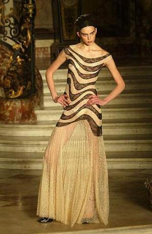 La versión estival 2003 del tradicional traje de chaqueta de 'tweed', ideado el siglo pasado por la fundadora de la casa, la legendaria 'mademoiselle Coco', se deshará en bordados hasta difuminar puños, mangas, faldas y chaquetas en etéreo tul rosado y transparente, cortado al ras o levemente deshilachado
Diseño del modista: Julian McDonald