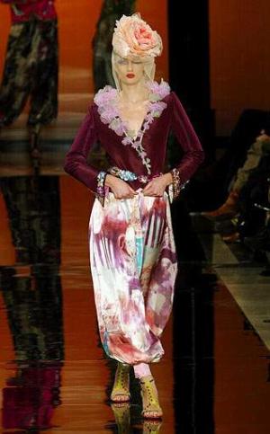 Portando chalecos decorados con motivos de lentejuelas y piedras preciosas multicolores, sobre blusas y faldas de estilo gitano, o bajo conjuntos de puntillas bordados en turquesa, naranja, rosa y fucsia, el verano 2003 sirvió de excusa a Ungaro para dar rienda suelta a sus más bellas fantasías.


Diseño del modista: Ungaro