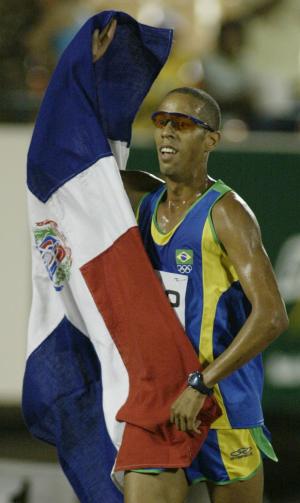 Hudson de Souza levanta la bandera de República Dominicana después de haber ganado la medalla de oro en los 5,000 metros.