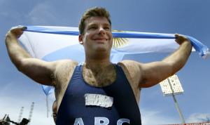 El argentino Juan Cerra festeja con la bandera de su país después de haber ganado la medalla de oro en lanzamiento de martillo.