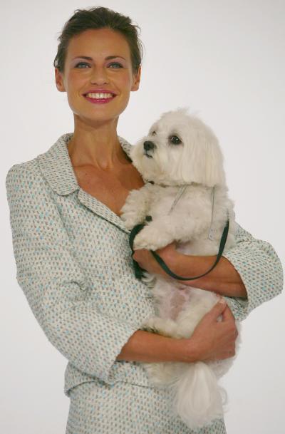 Una modelo desfila con un traje del diseñador Jean Muir acompañada de un pequeño cachorrito.