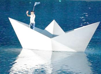 Un niño en un barco de papel recorrió la réplica del Mar Mediterráneo hasta llegar a la orilla, momento en el que se izó la bandera y sonó el himno nacional griego.