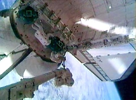El astronauta Stephen Robinson, montado en el extremo de un brazo robótico de 50 metros de largo, retiró suavemente dos trozos de fieltro de relleno que sobresalían entre las losas de protección térmica del transbordador 'Discovery'.