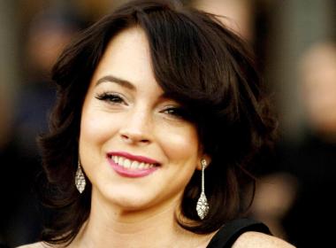 Lindsay Lohan sonríe a la prensa.