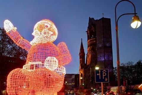 Un enorme Santa Claus iluminado  fue captado al oeste de la ciudad de Berlín, Alemania. Detrás de la silueta está la iglesia Memorial Kaiser Wlhelm.