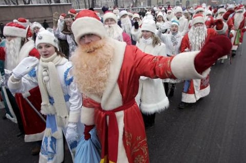 Varios hombres disfrazados de Santa  y mujeres vestidas de 'Doncella de la Nieve'  participan en un desfile por las principales calles de Minsk Bielorrusia.