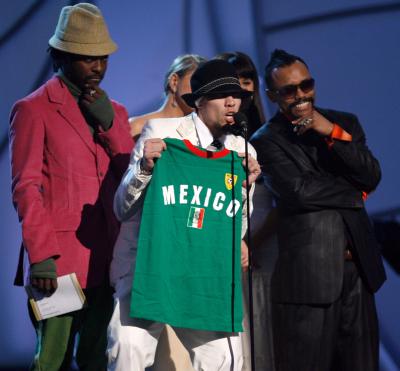 El grupo Black Eye Peas muestra una camiseta de futbol con el nombre de México al momento de recibir su premio.