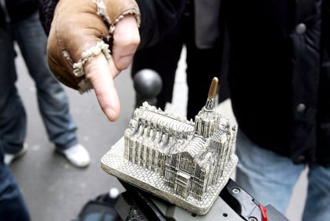 Un hombre señala una réplica del Duomo de Milán, normalmente vendido como 'souvenir' en la ciudad, objeto que un hombre arrojó al primer ministro italiano, Silvio Berlusconi.