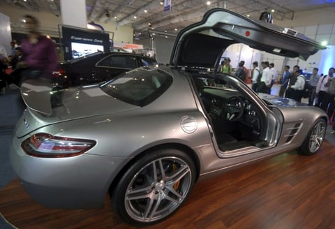 Varias personas observan el modelo SLS AMG de Mercedes Benz.